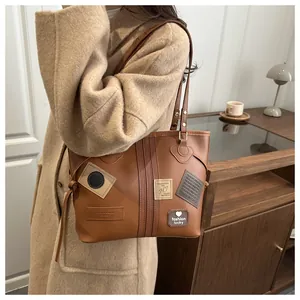 Detail of vintage brown PU leather tote bag with retro patches and stylish heart embroidery