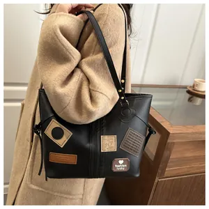 Detail shot of black faux leather tote bag with vintage patches and textured finish