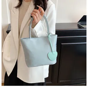Detail view of water-resistant light grey nylon tote bag with a green heart charm