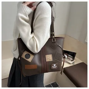 Detail of vintage brown PU tote bag with decorative fashion patches and shoulder strap