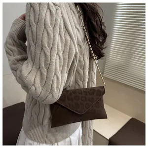 Détail d'un sac bandoulière léopard avec chaîne dorée sur fond de pull en maille douce