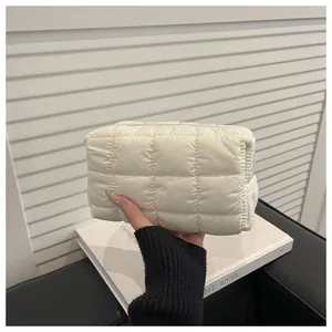 Detailed view of cream nylon quilted cosmetic bag showing soft padded texture and zipper