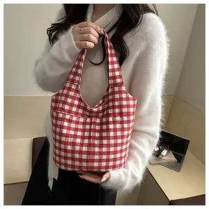 Detail of red and white checkered canvas tote bag with front pockets on female model