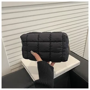 Detail of black quilted nylon makeup bag with golden zipper and puffer texture