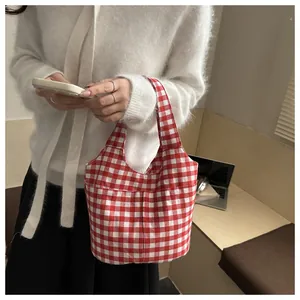 Detail view of red and white gingham canvas tote bag held in a cozy lifestyle setting