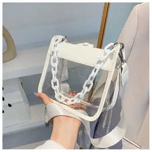 Detail of transparent PVC crossbody bag featuring white leather trim and chunky chain strap