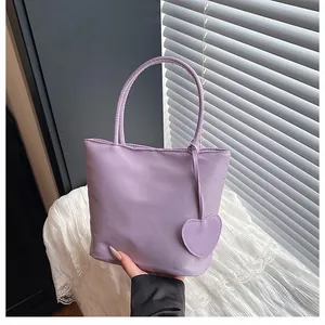 Detail of light purple tote bag featuring a matching heart charm and smooth texture