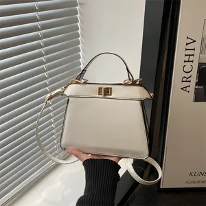 Elegante beige Lederhandtasche in Trapezform mit goldenem Drehverschluss und Schultergurt