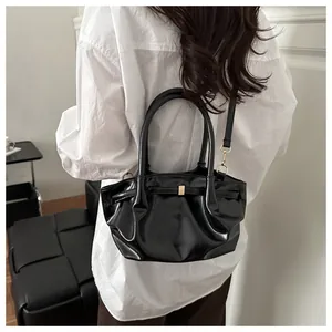 Détail du sac à bandoulière noir brillant avec ferrures dorées et texture à plis froncés