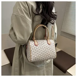 Détail d'un sac Boston à motif géométrique porté avec un trench-coat kaki élégant