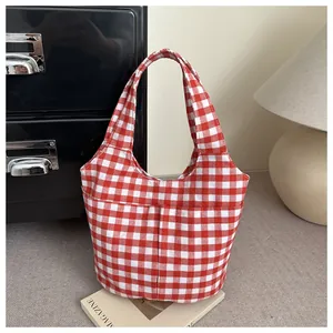 Detail of red and white checkered canvas tote bag with matching handles on a magazine