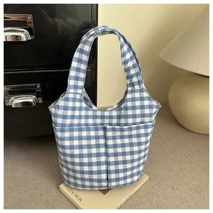 Detail of blue and white gingham tote bag featuring two front utility pockets on canvas