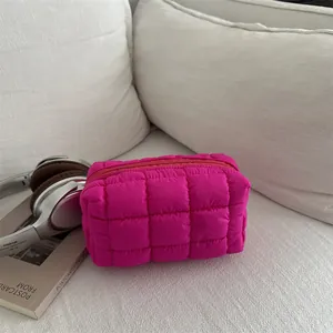 Rose red quilted nylon makeup bag with puffy grid design and zipper closure on a white surface