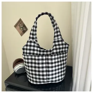 Detail of checkered canvas tote bag with functional exterior pockets in a cozy setting