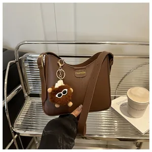 Close-up of brown textured PU leather bucket bag with fashion label and bear charm