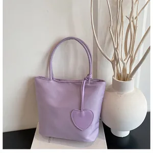 Close-up of lavender nylon tote bag featuring a heart pendant and slim round handles