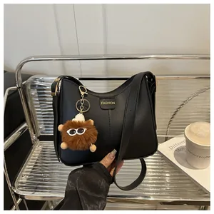 Detail of black leather bucket bag with gold 'FASHION' lettering and plush charm