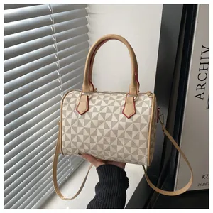 Detailaufnahme einer Handtasche mit geometrischem Muster, Ledergriffen und roten Kanten