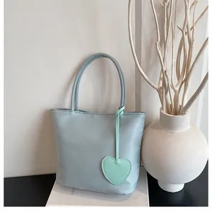 Detail of light blue minimalist tote bag with smooth handles and heart shaped charm
