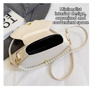 Detail view of shell-shaped crossbody bag with pearl handle and spacious interior