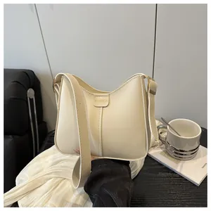 Close-up of cream leather hobo bag with gold metal buckle and adjustable strap