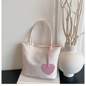 Close-up of beige tote bag with a pink leather heart charm in a minimalist interior