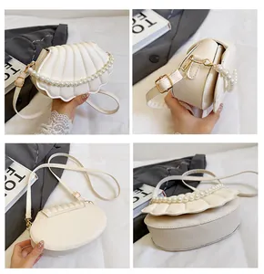 Detail view of white shell-shaped bag with pleated design and decorative pearl chain