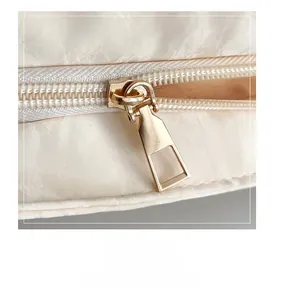 Détail de la fermeture éclair dorée sur le sac à bandoulière matelassé blanc