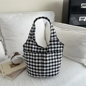 Minimalist black and white checkered canvas tote bag with front pocket on a white sofa