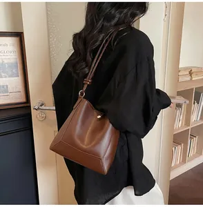 Detail of a vintage dark brown leather tote bag showing textured material and bucket shape