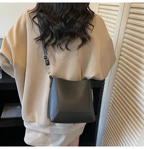 Detail view of black matte leather bucket bag with adjustable strap on model