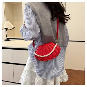 Close-up of a red shell-shaped crossbody bag featuring pearl chain and pleated texture