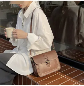 Close-up of a vintage brown leather bag featuring contrast stitching and metallic bar lock