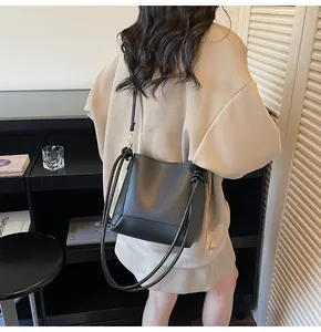 Detail of minimalist black leather bucket bag with unique knotted shoulder strap and sleek texture