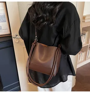 Detail view of deep brown leather tote bag showing minimalist texture and cylindrical handle