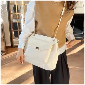Détail du sac sous l'aisselle blanc crème avec boucle dorée et bandoulière chaîne