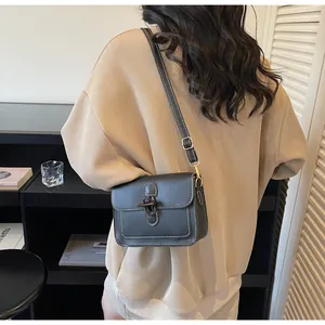Detail of black crossbody bag featuring contrast white stitching and horn buckle closure