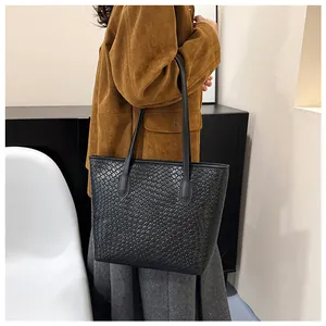 Detailed close-up of the black woven leather texture on a stylish tote bag shoulder strap