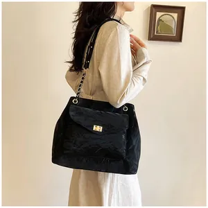 Détail du sac cabas noir plissé avec bandoulière dorée et fermoir pivotant sur modèle