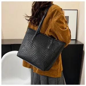 Detailed view of black woven texture on a large capacity tote bag worn with a brown jacket