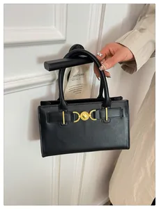 Close-up of black matte leather handbag with vintage gold heart buckle on a door handle