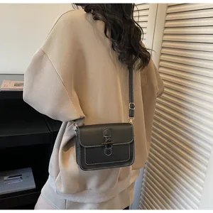 Detail of black leather crossbody bag with horn buckle closure and white contrast stitching