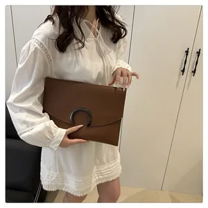 Detail of a brown synthetic leather tote with a stylish black crescent-shaped buckle closure