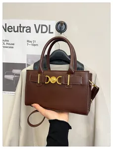 Detail of dark brown leather handbag with gold heart-shaped buckle and crossbody strap