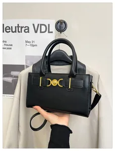 Detail of black leather handbag featuring vintage gold heart hardware and dual handles