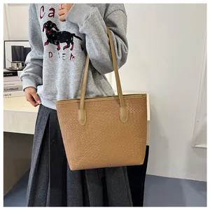 Detail of camel tote bag with woven texture worn by model in a minimalist setting