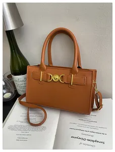 Detail of caramel brown leather handbag with gold heart buckle on vintage book