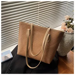 Detailed view of brown tote bag with woven texture on a stylish workspace setting