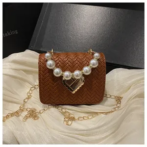 Detail of woven straw mini bag with pearl handle and golden heart clasp on black box