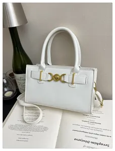 Close-up of white minimalist handbag with gold heart buckle and adjustable strap